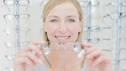 Woman trying on glasses in optometrists shop