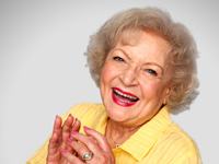 Betty White laughing in a yellow blouse