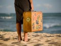 woman carrying suitcase on beach