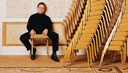 Albert Brooks with stacks of chairs.