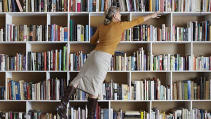 AARP Bookstore - woman reaches for book on bookshelf