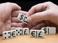 Unas manos organizan unas fichas de dominó con símbolos de dólar, euro y libra esterlina.