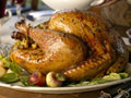 Stuffed turkey on table, woman serving green beans (USA)