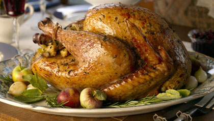 Stuffed turkey on table, woman serving green beans (USA) Stuffed turkey on table, woman serving green beans (USA)