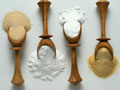 Four wooden spoons with various baking ingredients