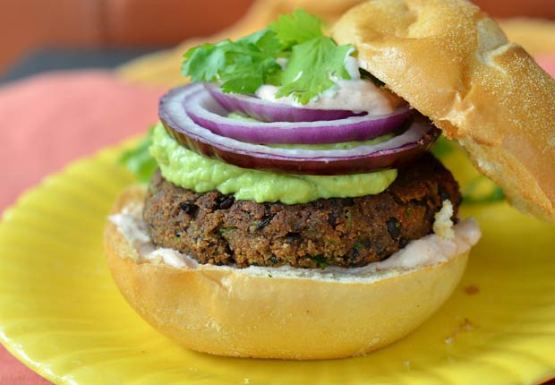 Hamburguesa de frijoles negros con cebolla roja, guacamole y salsa cremosa.