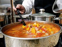 A male cook stirs food in his home kitchen, Cookster one pot meals.