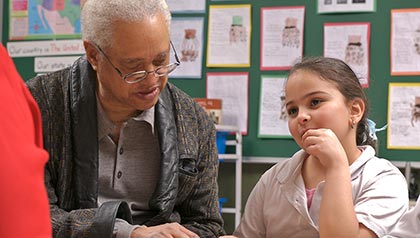 Senior man explains book to child, AARP Experience Corps