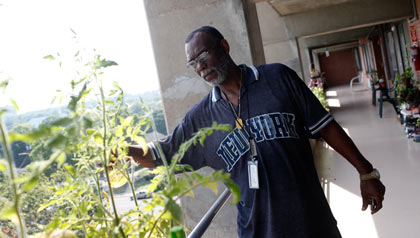 Charles Houston waters a tomato plant he’s growing to help supplement the government assistance he gets to buy food. Charles Houston waters a tomato plant he’s growing to help supplement the government assistance he gets to buy food.