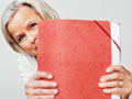 a senior woman holds a file folder full of papers