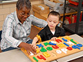 A woman and child play alphabet game, AARP Experience Corps History