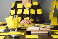 A woman with post-it notes all over her body and her desk. A woman with post-it notes all over her body and her desk.