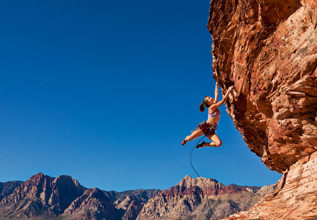 Female rock climber hanging on edge