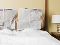 couple in bed reading newspaper - 7 Meds That Can Wreck Your Sex Life