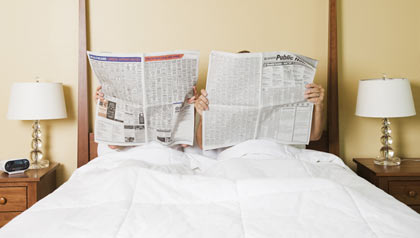 couple in bed reading newspaper - 7 Meds That Can Wreck Your Sex Life