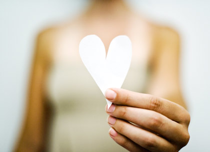 Woman's hand holding out paper heart Woman's hand holding out paper heart