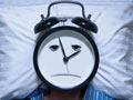 man with alarm clock head having trouble sleeping