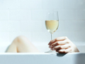 Woman relaxing with glass of wine in tub. Will drinking alcohol increase your risk of developing breast cancer?