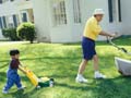 Abuelo y nieto cortando el césped en el jardín de su casa