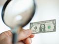 Examining a shrunken dollar with magnifying glass