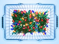 Illuminated Christmas lights in shopping basket on blue background
