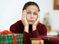 disillusiond woman at christmas with lots of wrapped gifts