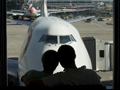 Couple looks out airport window - one needs to search for senior airfares and many are not online