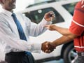 Vendedor dando las llaves de un coche nuevo a un hombre - Cómo comprar un coche con el precio más bajo posible