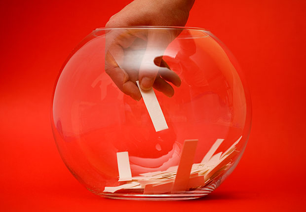 A hand reaches for names in a fishbowl, frugal holiday season ideas