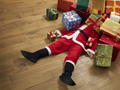 Santa Claus being crushed by holiday gifts.