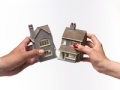 Man and woman holding toy house split in half.