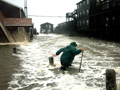 IRS Gives Tax Relief in Hurricane Zone- a motel owner wades into the flooding waters created by Hurricane Irene to clear the drains in his parking lot