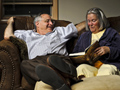 A couple enjoys the pleasure of reading out loud on the couch.