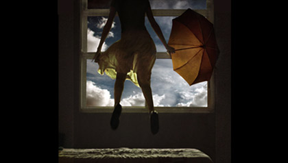 girl jumping inside on bed with umbrella