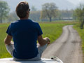 Man sits in outdoor setting in reflective pose