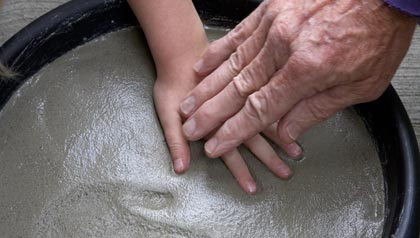 Manos de un abuelo prensa las de su nieto en el cemento para hacer impresiones - 8 Actividades de Ciencia divertidas para hacer con sus nietos