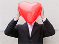 Hombre tapándose la cara con un globo en forma de corazón 