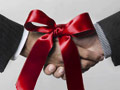 Hands shaking with red bow - Congressional budget deal analysis