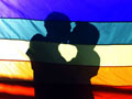 Two men embrace behind a rainbow flag, Same Sex Rights