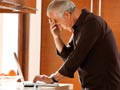 man in kitchen with laptop, cell phone and headset