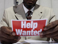 man holds up a help wanted poster