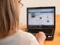 A woman using a notebook computer looks at a Facebook page.