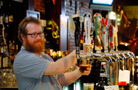 Bartender pours a pint from one of 20 taps at a bar in Brooklyn
