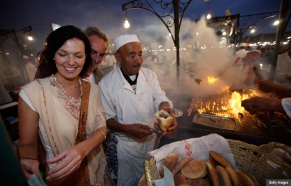 Couple eating food at a market in Marrakesh, Morocco.
