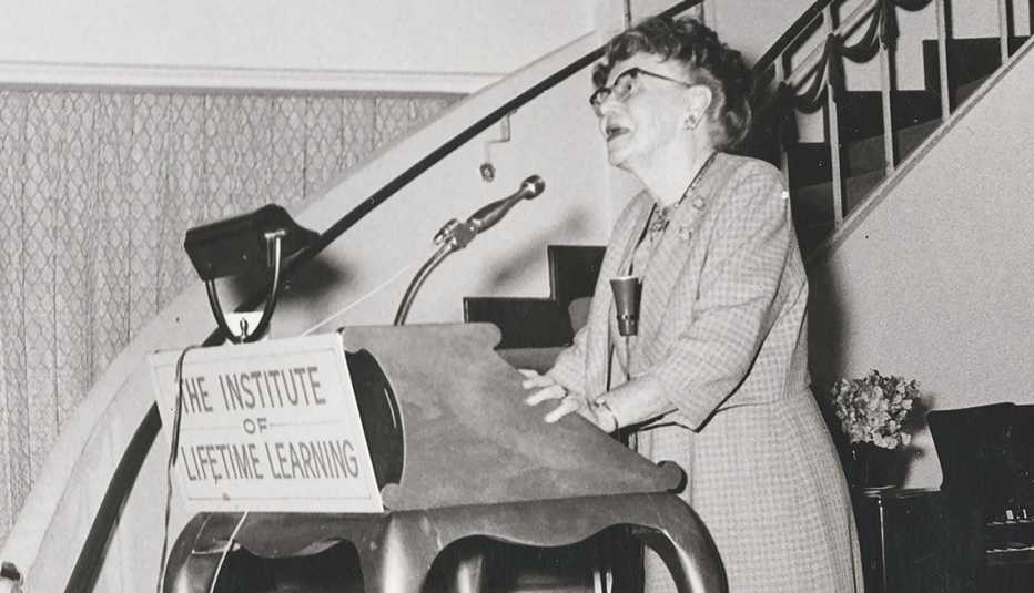 Dr. Ethel Percy Andrus standing at podium that reads "The Institute of Lifetime Learning"