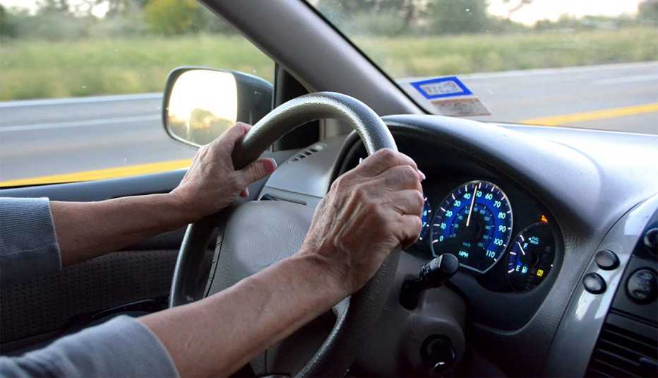 A senior woman's hands holding the steering wheel of a vehicle