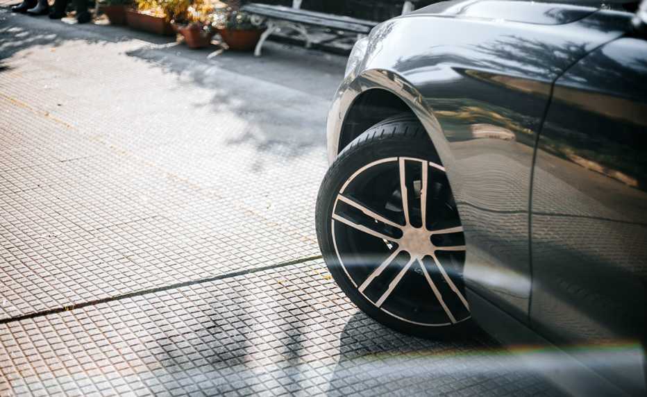 the front end of the left side of a gray car and its wheel