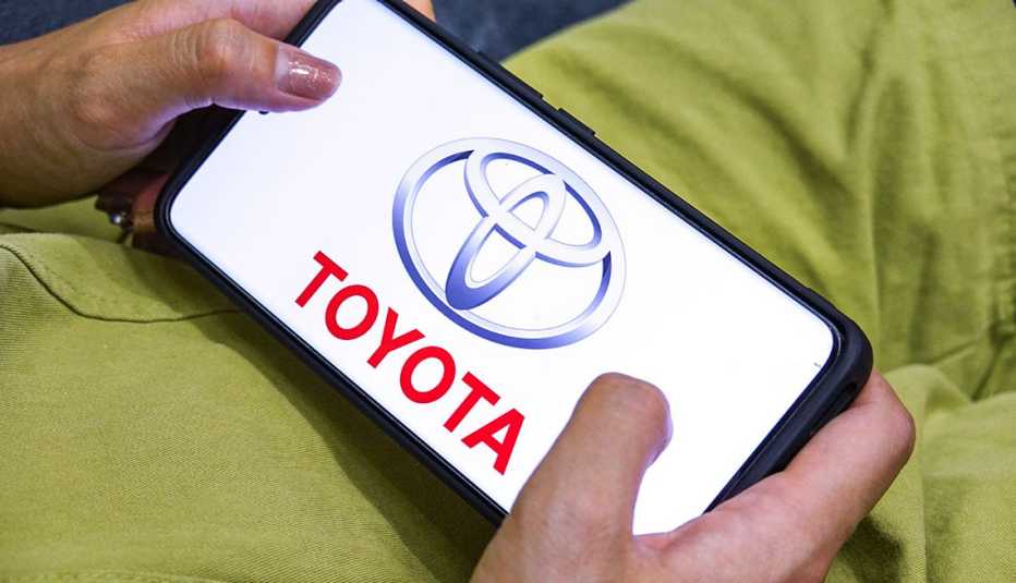 a person in green holds a smartphone displaying a toyota logo