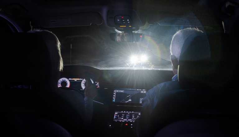 a woman and man driving at night cannot see well due to an oncoming car having its brights on