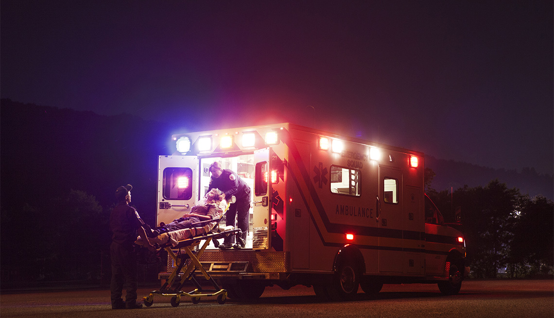 Emergency medical services workers putting putting a patient in an ambulance